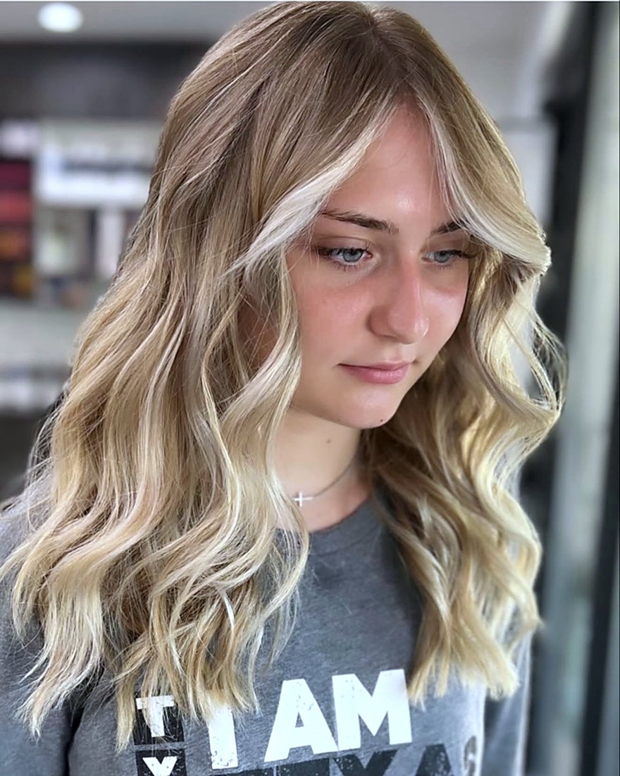 Dimensional brunette-to-blonde color and soft waves created at Hello Gorgeous Hair Lounge